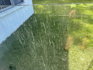 Dirty glass fence panels with water spotting before cleaning in Glenella