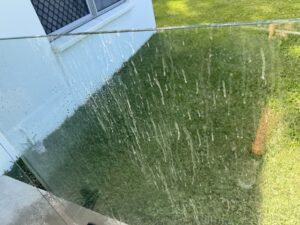 Water-stained outdoor glass fencing before professional glass cleaning