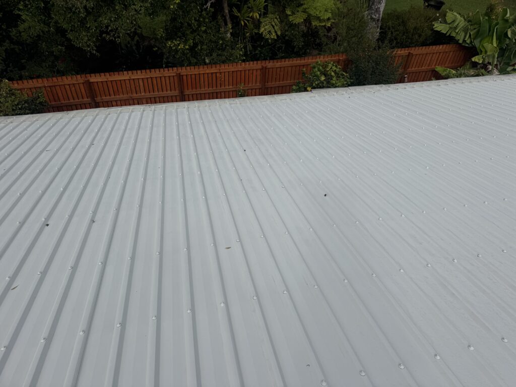 Light-coloured metal roof beside garden and timber fence
