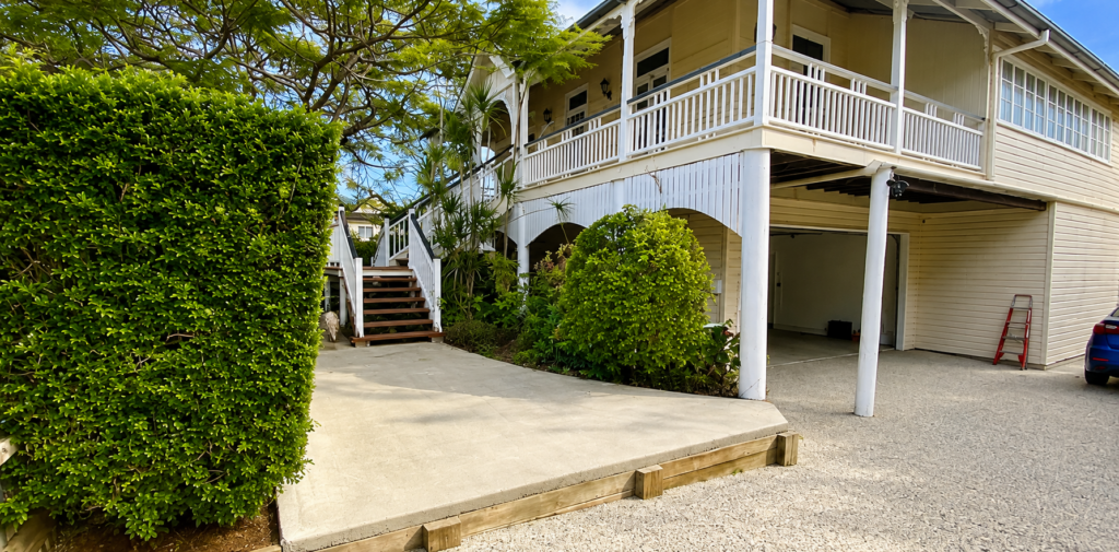 Raised weatherboard home with white verandah balustrades and timber front stairs