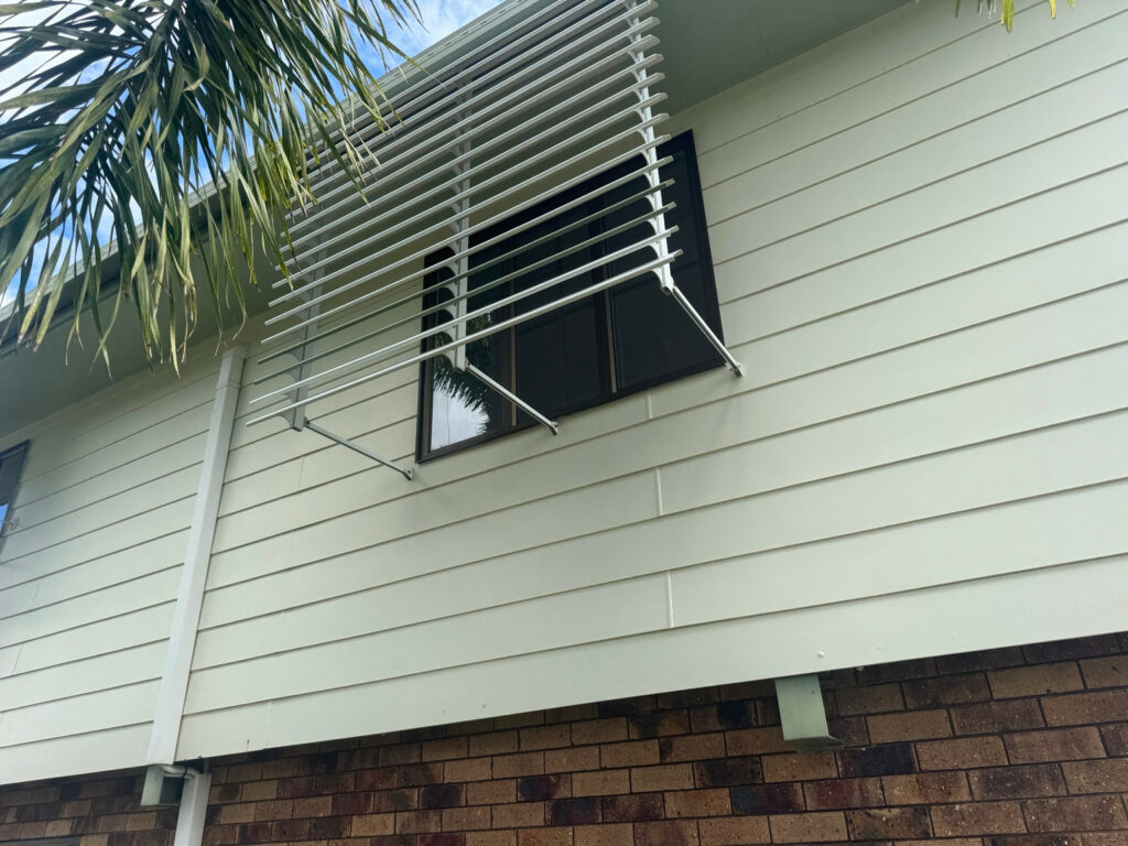 Pale projecting slatted window awning with support arms