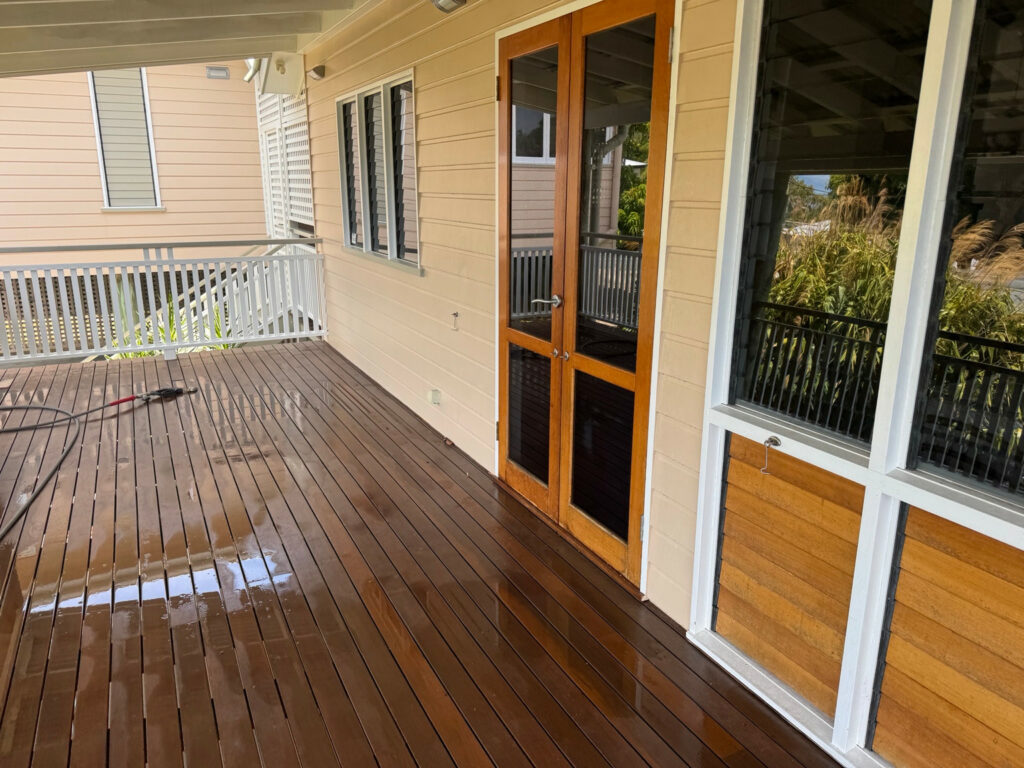 Wet timber deck beside glazed timber doors and white verandah balustrades