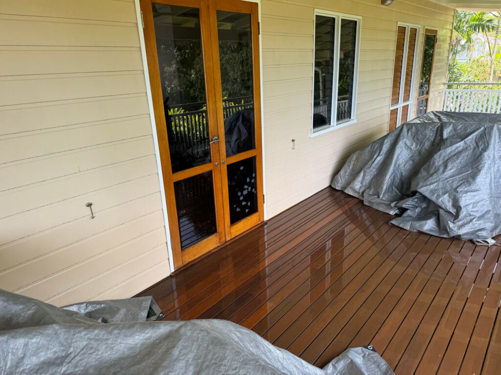 Timber verandah floor beside house walls and covered outdoor furniture