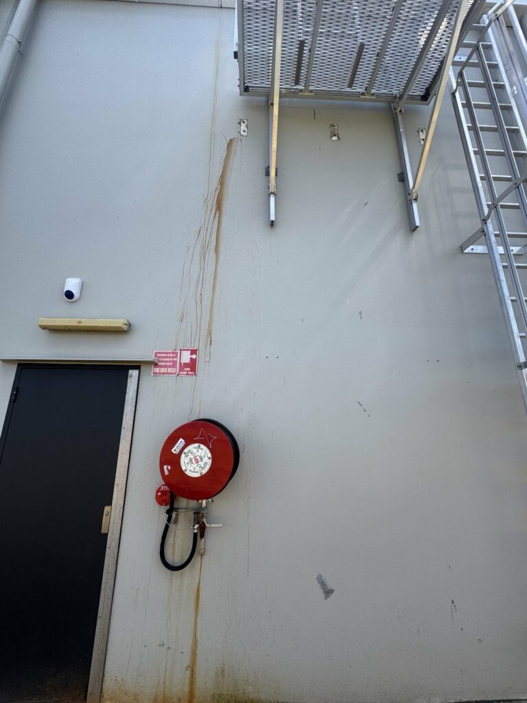 Rust marks below a metal access platform on a building wall at Windmill Crossing in North Mackay