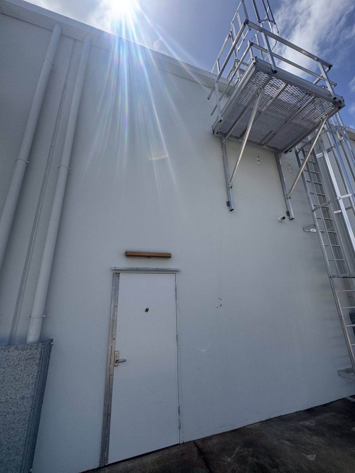 Light-coloured wall and white door beneath an access platform at Windmill Crossing