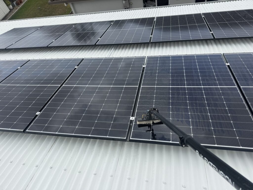 Brush cleaning solar panel faces on a Glenella roof